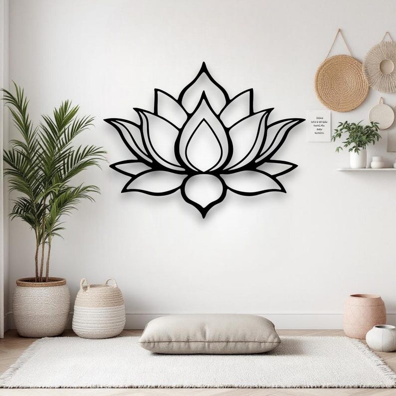 May include: A black lotus flower wall art piece. The floral design is mounted on a white wall. The room is decorated with plants, a rug, and decorative baskets. The lotus flower is a symbol of purity, enlightenment, self-regeneration and rebirth.