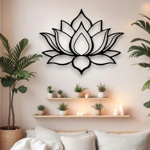 May include: A black lotus flower wall art decor. The metal art piece is mounted on a light-colored wall. The image also shows plants, shelves, and candles, creating a serene and natural ambiance.