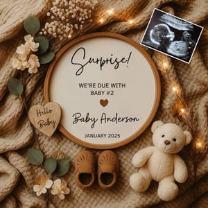 May include: A pregnancy announcement with a round wooden sign that reads "Surprise!" and "We're due with Baby #2." The announcement includes a sonogram, baby shoes, a teddy bear, and a wooden heart that says "Hello Baby."