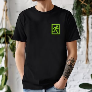 May include: Black t-shirt featuring a neon green exit sign graphic on the upper left chest. The graphic depicts a running person inside a square frame. The shirt is made of a soft material and has short sleeves.