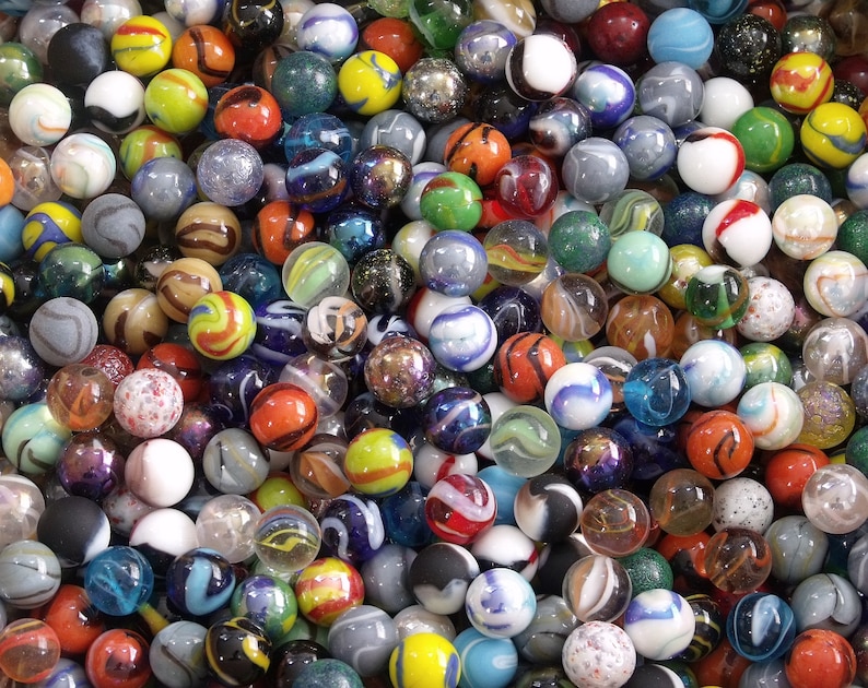 May include: A large collection of colorful glass marbles in various sizes and patterns. The marbles are arranged in a random pattern, creating a visually appealing and textured surface.