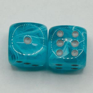 May include: Two turquoise dice with a marbled effect and silver pips. One die shows three pips, the other shows five. The dice are square and have rounded edges. The dice are set against a white background.