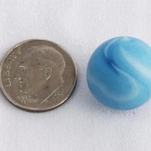 May include: A blue and white marble with a swirling pattern. The marble is about the size of a US dime.