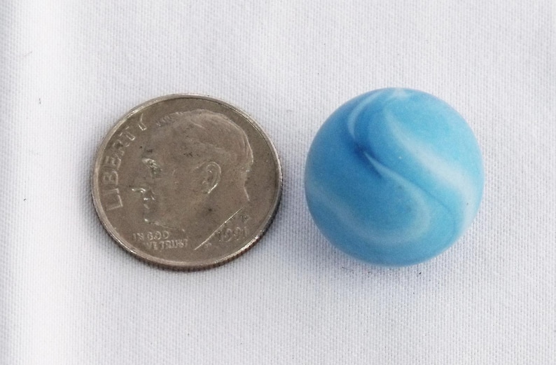 May include: A blue and white marble with a swirling pattern. The marble is about the size of a US dime.