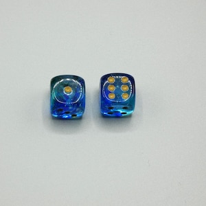 May include: Two blue and clear dice with gold dots. The dice are on a white surface.