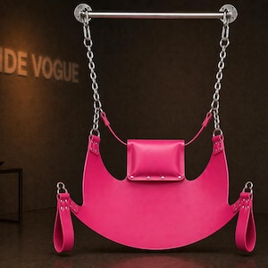 May include: A hot pink leather swing suspended from a silver bar by chains. The swing has a curved seat, a small square pillow, and straps. The words "HIDE VOGUE" are visible on the wall.