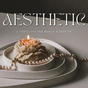 May include: Aesthetic image with a lit, flower-shaped candle on a white plate, with a pearl necklace and the word "AESTHETIC" in the background. The text "5 VIDEO LUTS FOR MOBILE & DESKTOP" is also visible.