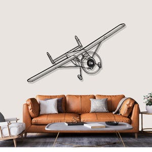May include: A black metal airplane wall art piece. The artwork shows a vintage biplane with detailed wings, a propeller, and landing gear. The plane is mounted on a neutral-coloured wall above a brown leather sofa.