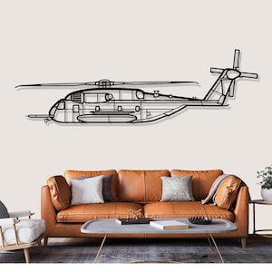 May include: Black metal helicopter wall art. The artwork shows a detailed outline of a helicopter, including the main rotor, tail rotor, and fuselage. The helicopter is mounted on a neutral-coloured wall above a brown leather sofa.