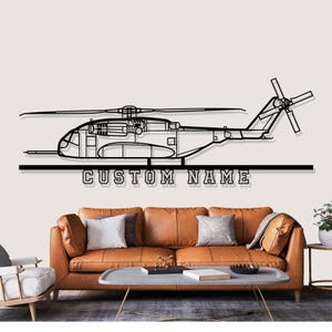 May include: Black metal helicopter wall art with the text "CUSTOM NAME" below the helicopter. The helicopter has detailed cutouts of the interior. The wall art is displayed above a brown leather sofa.