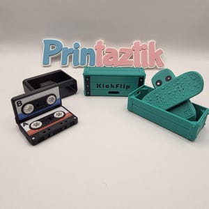 Puede incluir: Una colección de objetos impresos en 3D, que incluye una cinta de cassette, un pequeño cofre verde azulado con el texto "KickFlip" y un monopatín verde azulado. La palabra "Printaztik" se muestra en letras azules y rosas.