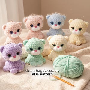 May include: A collection of handmade crochet kitten bag accessories in various pastel colors, including pink, blue, green, yellow, and purple. Each kitten has large eyes and a small pink nose. A ball of green yarn and a crochet hook are also present.