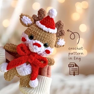 May include: A handmade crochet reindeer with a red scarf and Santa hat. The reindeer is brown, white, and red, with large black eyes. The image includes the text "crochet pattern in Eng" and a PDF icon.