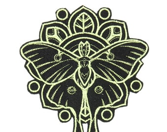 May include: A black and green embroidered patch of a moth with a mandala design. The moth has long antennae and intricate wings.
