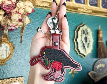 Llavero bordado de cuervo y rosa - Piel sintética color rojo intenso con herrajes en tono bronce