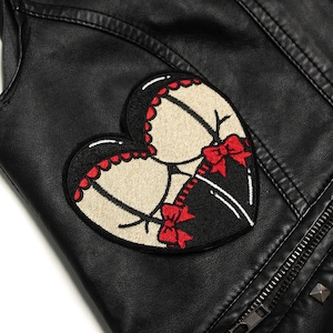 May include: Black leather jacket with a heart-shaped embroidered patch featuring a corset design with red bows.