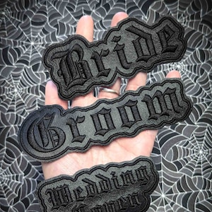 May include: Three black leather patches with gothic lettering. The patches read "Bride", "Groom", and "Wedding Coven".