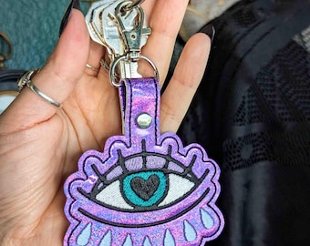 Llavero de globo ocular lloroso - Vinilo holográfico lavanda con herrajes plateados