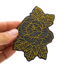 May include: Black leather patch with a gold embroidered peony flower design.
