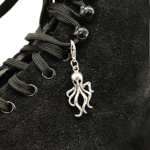 May include: Black suede skate shoe with black laces and a silver octopus charm attached to the laces.