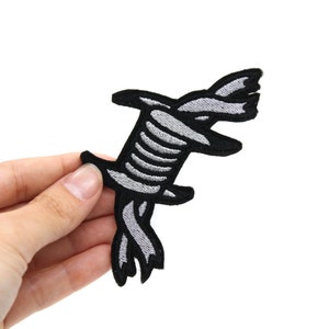 Puede incluir: Un parche de hierro bordado en negro y gris con un diseño de alambre de púas.