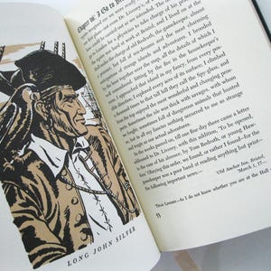 Pode incluir: Um livro aberto com uma ilustra&ccedil;&atilde;o a preto e branco de Long John Silver, um pirata, com um papagaio no ombro. O texto "LONG JOHN SILVER" est&aacute; por baixo. O livro est&aacute; aberto num cap&iacute;tulo com texto.