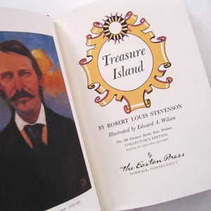 Pode incluir: Livro aberto com um retrato e o t&iacute;tulo "Treasure Island". O t&iacute;tulo est&aacute; em uma moldura dourada com um desenho de sol. O livro &eacute; uma edi&ccedil;&atilde;o de colecionador, encadernado em couro genu&iacute;no.