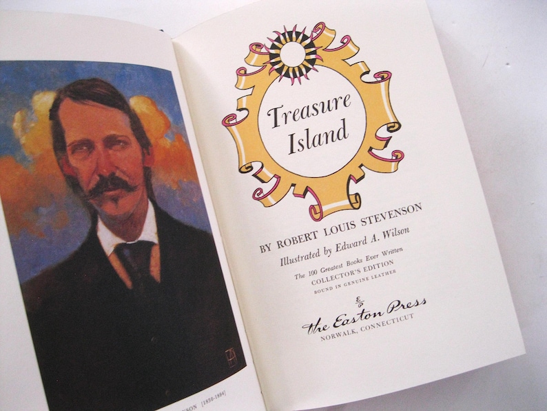 Pode incluir: Livro aberto com um retrato e o t&iacute;tulo "Treasure Island". O t&iacute;tulo est&aacute; em uma moldura dourada com um desenho de sol. O livro &eacute; uma edi&ccedil;&atilde;o de colecionador, encadernado em couro genu&iacute;no.