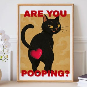 Könnte beinhalten: Gerahmter Kunstdruck mit einer Illustration einer schwarzen Katze mit einem roten Herz auf dem Hintern. Der Text "ARE YOU POOPING?" ist rot. Das Kunstwerk hat einen Vintage-Stil mit beigem Hintergrund.