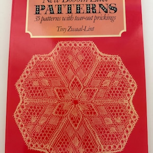 May include: A red book titled "New Bobbin Lace PATTERNS" with a cream-colored, intricate lace design on the cover. The book includes 35 patterns with tear-out prickings by Tiny Zwaal-Lint. The cover features a detailed, symmetrical lace pattern.