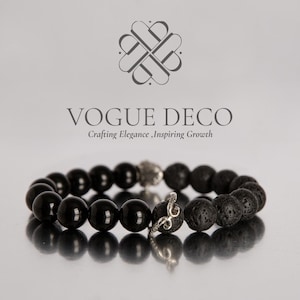 May include: A black beaded bracelet with a silver accent piece and a decorative charm. The bracelet features a mix of smooth, glossy beads and textured lava beads. The brand name "VOGUE DECO" is displayed above the bracelet.