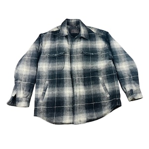 Op de afbeelding: Een witte keramische mok met een zwart handvat en de tekst "But First, Coffee" in een vetgedrukte, zwarte letter. De mok staat tegen een vage achtergrond, wat een gezellige setting suggereert.