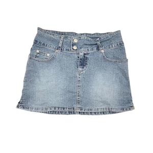 May include: A light blue denim skirt with a high waist design. The skirt features two front pockets, two decorative buttons, and a classic five-pocket style. The skirt is made of a durable denim material.