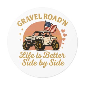 Peut inclure: Autocollant rond avec un graphique d'un véhicule tout-terrain avec un drapeau américain. Le texte dit "Gravel Road'n" et "Life is Better Side by Side" dans un style vintage. Le fond présente un coucher de soleil et des coeurs.