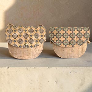 Può includere: Due borse semicircolari realizzate in sughero color marrone chiaro naturale. La borsa a sinistra presenta un motivo geometrico a piastrelle blu scuro e giallo sulla patta. La borsa a destra mostra un motivo a quadrifoglio verde e arancione.