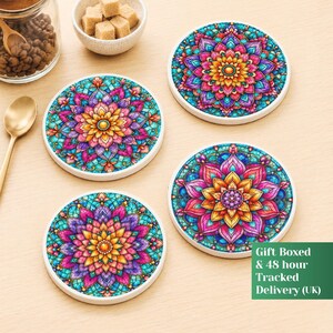 May include: Four circular ceramic coasters featuring a vibrant, multi-coloured mandala pattern with shades of pink, purple, yellow, and teal. Each coaster displays a symmetrical floral design with intricate petal-like details and a central golden circle.