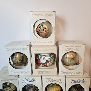 May include: A collection of vintage Christmas ornaments in their original boxes. The boxes feature text such as "Santa's Surprise" and "Christmas 1979." The ornaments have various designs, including cherubs, Santa Claus, and other festive scenes.