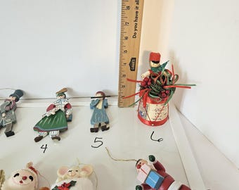 May include: A collection of Christmas ornaments, including a Santa Claus figure, a mouse in a red hat, and various other festive figurines. A wooden ruler is in the background, measuring up to 11 inches.