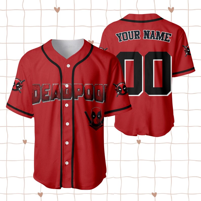 Op de afbeelding: Rood honkbalshirt met zwarte afwerking en witte knopen. De voorkant toont het woord "DEADPOOL" in een vetgedrukte, omlijnde letter, samen met het Deadpool-logo. De achterkant heeft de tekst "YOUR NAME" boven het nummer "00".