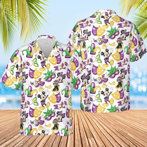 May include: White button-down shirt featuring a repeating pattern of Mickey and Minnie Mouse characters, masks, and jester hats in purple, yellow, and green. The shirt has short sleeves and a classic collar.