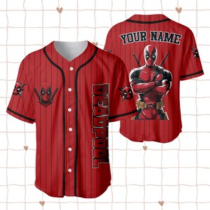 Op de afbeelding: Rood honkbalshirt met zwarte krijtstrepen, met Deadpool-graphics. De voorkant toont het Deadpool-logo en het woord "DEADPOOL" verticaal. De achterkant heeft een grote Deadpool-afbeelding en de tekst "YOUR NAME".