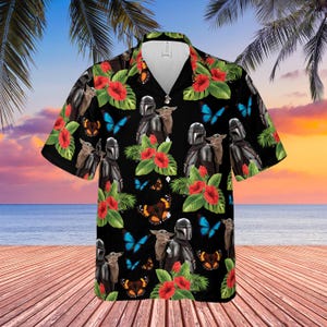 May include: Black short-sleeve button-down shirt with a tropical design. The shirt features a repeating pattern of The Mandalorian, Grogu, red hibiscus flowers, blue butterflies, and brown butterflies.