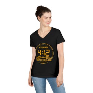 Könnte beinhalten: Schwarzes V-Ausschnitt-T-Shirt mit goldfarbener Grafik. Die Grafik zeigt das Wort "Pittsburgh" über den Zahlen "4:12" in einem Zifferblatt-Design, mit "Yinz on the Clock" und "2020 Draft" darunter. Das T-Shirt wird von einer Person getragen.