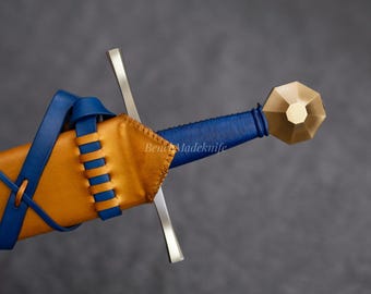 May include: A close-up of a sword with a blue leather-wrapped handle and a gold-coloured pommel. The sword is sheathed in a tan leather scabbard with blue leather accents. The blade is silver.
