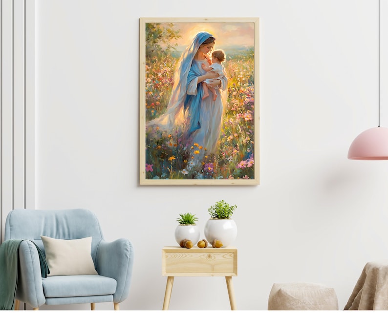 May include: A framed art print depicts a woman in a blue robe holding a child in a field of colorful flowers. The artwork has a soft, painterly style with warm lighting, creating a serene and spiritual atmosphere. The frame is a light wood color.