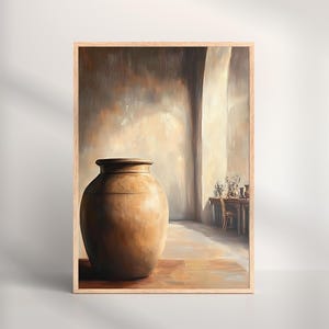 May include: A framed art print depicts a large, brown earthenware vessel in a sunlit room. The artwork features a neutral color palette with warm tones, a table with flowers, and a wooden frame.