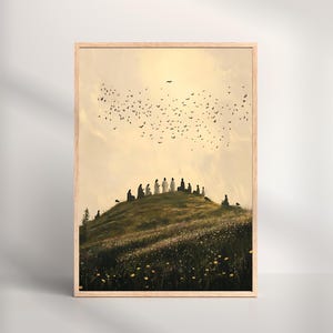 Puede incluir: Una impresión artística enmarcada que representa un paisaje sereno. Figuras silueteadas con túnicas blancas se reúnen en una colina cubierta de hierba, con una bandada de pájaros volando en el cielo dorado. La obra está enmarcada en madera clara.