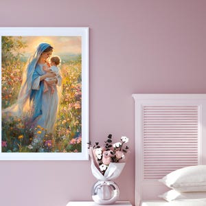 May include: A framed print depicts a woman in a blue veil holding a baby in a field of flowers. The artwork has a soft, ethereal quality with warm lighting. The color palette includes blues, yellows, and pinks, creating a serene and gentle scene.