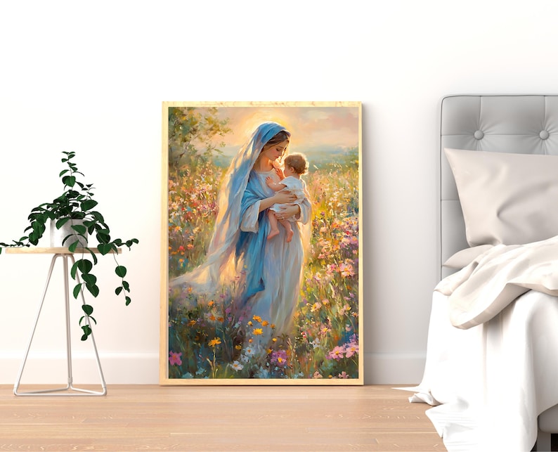 May include: A framed art print depicts a woman in a blue robe holding a baby. The artwork is set in a field of colorful wildflowers, with soft lighting and a warm color palette. The print is displayed on a wooden floor.
