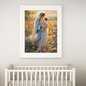 May include: A framed print of a woman in a blue veil holding a baby in a field of flowers. The artwork has a soft, painterly style with warm, natural colors. The white frame complements the artwork, creating a serene and peaceful atmosphere.